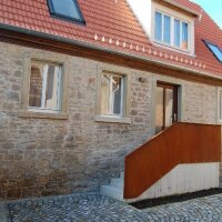 Das Foto zeigt den Eingangsbereich des saniertes Hauses mit Treppe und Natursteinfassade