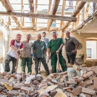 Sechs Arbeiter stehen auf einem Schuttberg im Gebäude während der Sanierungsarbeiten Sechs Arbeiter stehen auf einem Schuttberg im Gebäude während der Sanierungsarbeiten