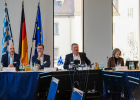 Vier Personen sitzen an einem Konferenztisch bei der Bauministerkonferenz in Würzburg