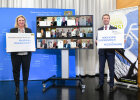 Gruppenbild der 15 neu ausgezeichneten fahrradfreundlichen Kommunen  (am Bildschirm) mit Bayerns Verkehrsministerin Kerstin Schreyer und AGFK-Vorsitzendem Matthias Dießl, die jeweils mit einem Gratulationsschild links und rechts vom Bildschirm stehen 