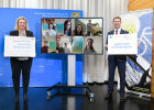 Gruppenbild der Gewinner der Aktion Schulradeln 2021 (am Bildschirm) mit Bayerns Verkehrsministerin Kerstin Schreyer und AGFK-Vorsitzendem Matthias Dießl, die jeweils mit einem Gratulationsschild links und rechts vom Bildschirm stehen 