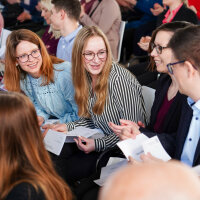 Mehrere junge Leute halten Zettel in der Hand und diskutieren