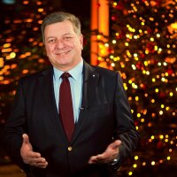 Staatsminister Christian Bernreiter steht vor dem Weihnachtsbaum im Ministerium