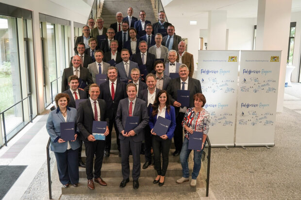 Gruppenfoto mit Verkehrsminister Christian Bernreiter und den Kommunalvertreterinnen und -vertretern für 27 Fahrrad-Projekte der Radoffensive "Klimaland Bayern". Sie stehen auf einer Treppe im Foyer des Bauministeriums . Die Kommunalvertreter halten jeweils eine Urkunde. Gruppenfoto mit Verkehrsminister Christian Bernreiter und den Kommunalvertreterinnen und -vertretern für 27 Fahrrad-Projekte der Radoffensive "Klimaland Bayern". Sie stehen auf einer Treppe im Foyer des Bauministeriums . Die Kommunalvertreter halten jeweils eine Urkunde.
