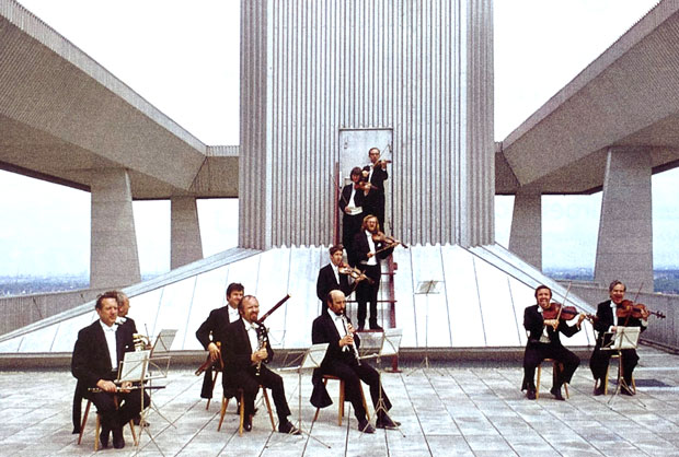 Ein Orchester spielt auf einem futuristischen Dach Ein Orchester spielt auf einem futuristischen Dach