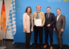 Verkehrsminister Hans Reichhart und Landtagspräsidentin Ilse Aigner übergeben den Förderbescheid an den Landrat von Miesbach, Wolfgang Rzehak. Im Bild zu sehen ist außerdem der Landrat von Ebersberg, Robert Niedergesäß.