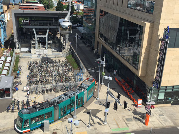 Station Integration Portland
Seilbahn Station inmitten einer Stadt. Die Gondel fährt über eine Radabstellanlage und eine fahrende Trambahn hinweg