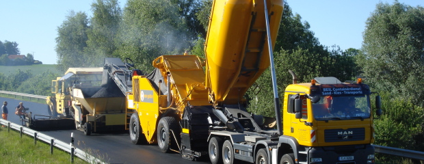 Asphalteinbau mit Beschicker und geschlossenem Mischgut-Transportfahrzeug Asphalteinbau mit Beschicker und geschlossenem Mischgut-Transportfahrzeug